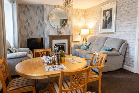 Cosy dining and living space with fireplace, recliner sofas, and complimentary coffee.