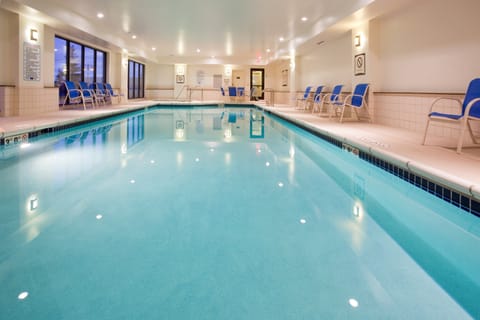 Indoor swimming pool with blue water and seating.