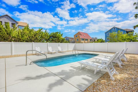 An inviting private swimming pool with ample lounge chairs awaits you on a sunny day, perfect for relaxing under the coastal sky.