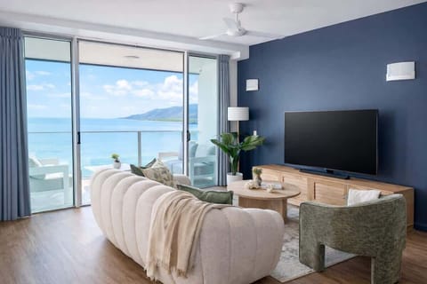 A modern yet comfortable living room space, fit with a 55 inch TV, and stunning water views of the coral sea