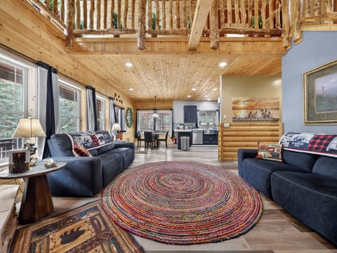Gather with your crew in this stunning open-concept cabin with soaring ceilings, rustic log beams, cozy sofas, and sunlight streaming through large windows—your mountain retreat awaits.