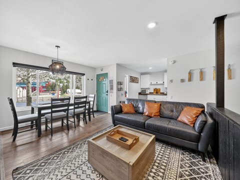 Relax in your open-concept living space where a plush leather sofa, natural light through expansive windows, and a cozy fireplace create the perfect retreat after a day of exploring.