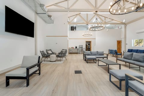 You'll love gathering in this spacious communal lounge with soaring beamed ceilings, plush seating, a large-screen TV, and elegant chandeliers creating a warm, inviting atmosphere perfect for relaxing together.