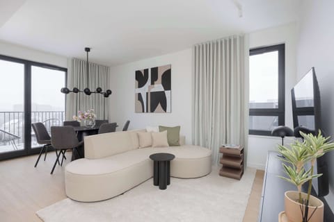 Bright, modern living room with floor-to-ceiling windows, elegant neutral décor, and a cozy curved sofa creating a warm and inviting atmosphere.