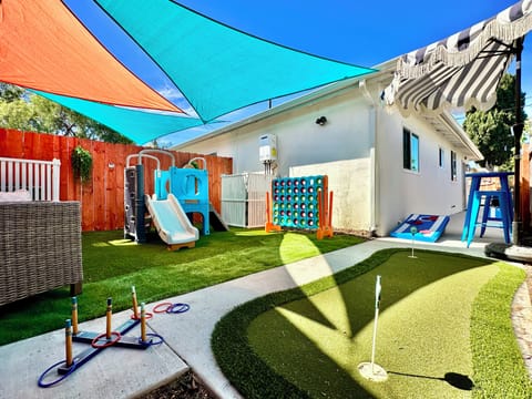Shaded yard with mini golf, a slide, cornhole and oversized Connect Four.