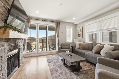 The great room opens onto the covered balcony, anchored by a floor-to-ceiling stone fireplace and plenty of seating to gather after a day out.