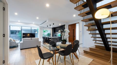 Open-plan dining and living area with furnishings and striking floating staircase