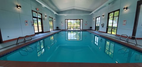 Indoor pool and adjacent hot tub area with tile surrounds and overhead lighting.