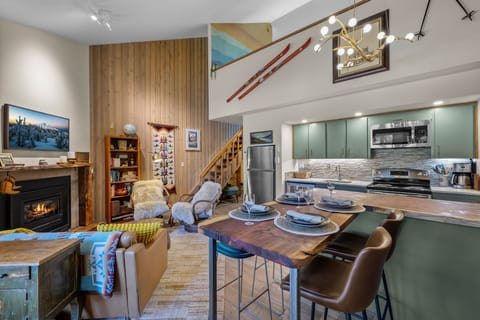 Gather around the rustic wood dining bar beneath soaring ceilings and warm ambient lighting, where you can prepare meals in your fully-equipped kitchen while staying close to the cozy fireplace and stylish living area.
