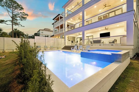Modern vacation home featuring a stunning private pool area with illuminated blue waters and spacious outdoor entertainment zones.