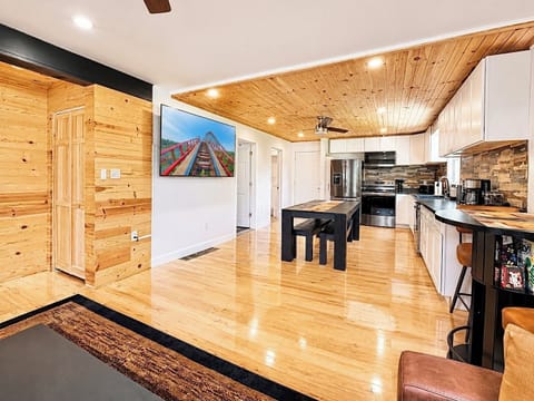 Open-concept living at its best—enjoy a spacious layout with warm wood accents, comfortable seating, and a large TV perfect for movie nights.