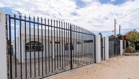 Large iron gate surrounds the property with a rock garden in the front yard and a shady lounge area by the front door