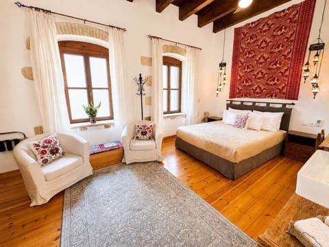 Bright bedroom with a comfortable bed, exposed wooden beams, and wooden furnishings, creating a warm and authentic atmosphere