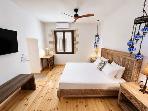 Elegant and bright bedroom featuring wooden floors, exposed beams, and Cretan-inspired décor. The space includes a comfortable bed, wooden furniture, and depending on the layout, a small seating area, creating a warm and authentic atmosphere