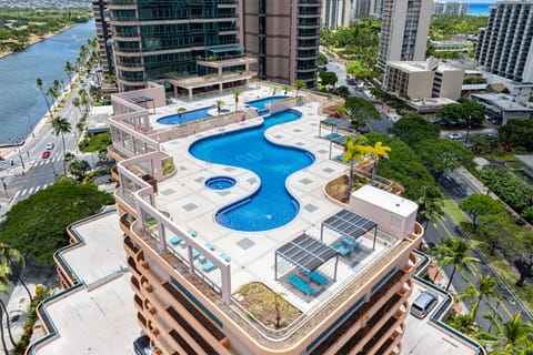 Up on the recreation deck, the resort pool curves past rows of loungers and swaying palms.