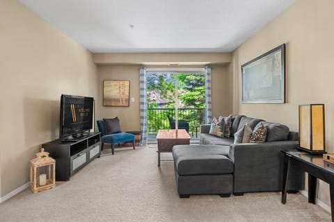 Open-concept living room with a Smart TV, a cozy sectional and walkout access to the balcony.