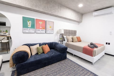 Cozy studio living area with a comfortable bed, couch, and modern decor.
