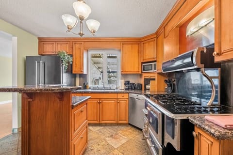 Full-featured kitchen with wooden cabinetry, granite counters, and stainless steel appliances.
