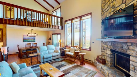 Unwind in this stunning mountain home with soaring ceilings and natural light. The cozy fireplace invites you to relax while you enjoy panoramic views through expansive windows.