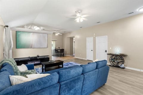 Spacious living room with a large sectional, electric fireplace, and massive 85” 4K Smart TV—perfect for relaxing together after a day at the beach.