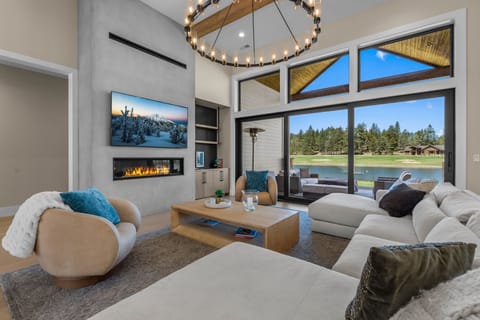 Every seat in the house has a view — the open living room offers comfortable seating for the whole group, a gas fireplace, and Tanager Lake as the backdrop.