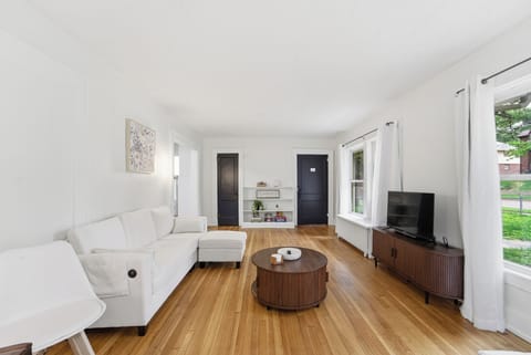 Bright, airy living room with hardwood floors, cozy lamp, and Smart TV