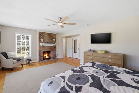 First-floor escape! A spacious king suite with an electric fireplace, three‑panel window views, walk‑in closet, Smart TV, and armchair. The spa‑style ensuite features a jacuzzi tub, large walk‑in shower, dual sinks, and a private water closet.