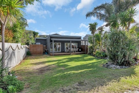 A classic Kiwi bach with a spacious, flat grass lawn and a large covered deck for relaxed outdoor dining.