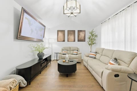 The front door opens into this serene living space—calm, neutral tones, plush leather seating, and a 75" Smart TV all inviting you to relax. 

A coat rack and entry table add both function and warmth to your welcome right alongside the entry door.