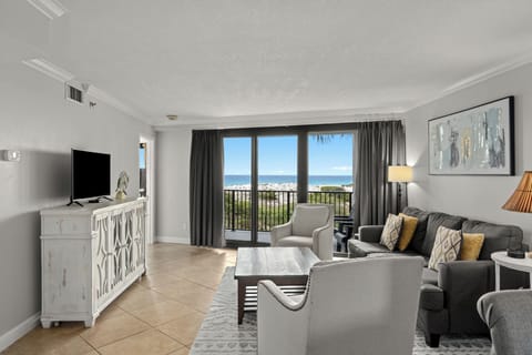 Relax in a bright Gulf-view living room with balcony access, comfortable seating, and coastal style.