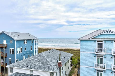 Coastal beachfront property showcasing oceanfront access and neighboring vacation homes along sandy shores with dune grass and rolling waves under open skies.