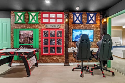 Experience a lively game room filled with colorful decor and fun features. Bright red and green accents enhance the sleek gaming chairs, and the air hockey table encourages friendly competition among guests.