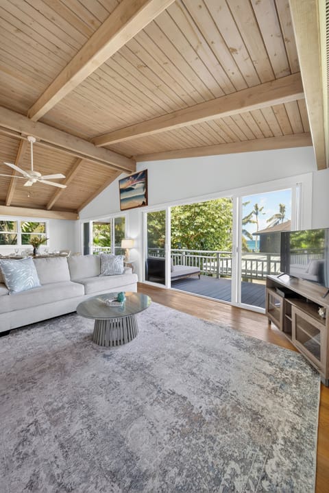 Relax in the bright open living room with soaring wood ceilings and tropical breezes.