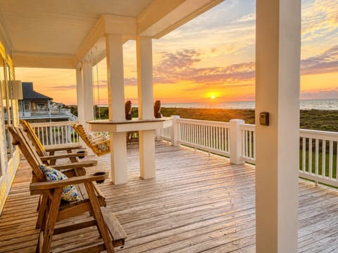 Spacious covered beachfront deck with rocking chairs and panoramic sunset views overlooking the Bolivar Peninsula marshlands near Crystal Beach, Texas.