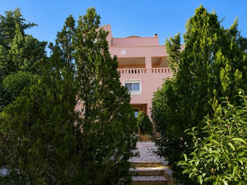 Sunny exterior view surrounded by trees and shared garden areas, creating a relaxing setting for holidays on Salamina Island throughout the entire year.