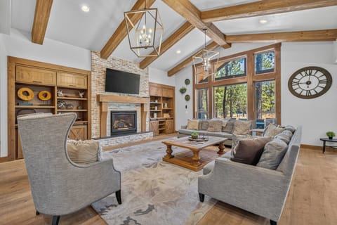 Settle into your spacious living room under soaring vaulted ceilings with exposed wood beams. Cozy up by the fireplace or simply relax on plush seating as natural light streams through the stunning floor-to-ceiling windows.