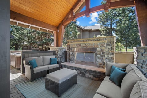 Relax on plush seating by a handsome stone fireplace in this covered outdoor lounge, where soaring timber beams frame mountain views and your own private hot tub awaits.