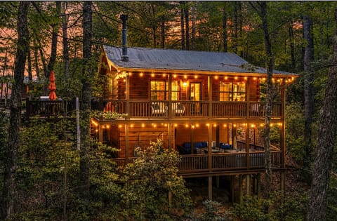 Cozy woodland cabin at dusk—string lights, two decks, tranquil views.