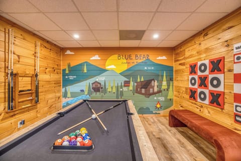Let the games begin! This epic cabin game room comes fully loaded with a sleek pool table, a wall-mounted giant Tic-Tac-Toe board, and comfortable bench seating. All set against the backdrop of a vibrant, custom local area mural.