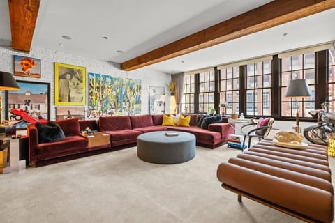 Modern loft-style space with stylish artwork, large windows, and a comfortable area to relax and entertain.
