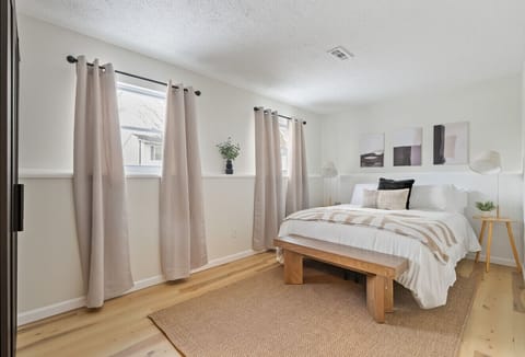 Relaxing bedroom with plush bedding, minimalist design, and large windows for natural light