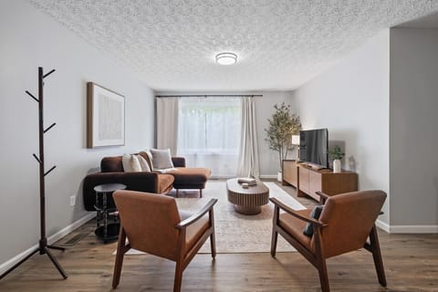Stylish living room with modern seating, smart TV, and large windows for natural light—perfect for relaxing
