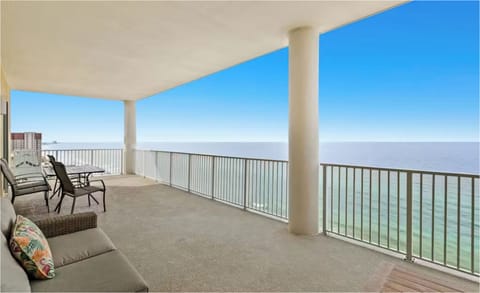 Expansive oceanfront balcony with outdoor seating overlooking pristine waters and clear skies.