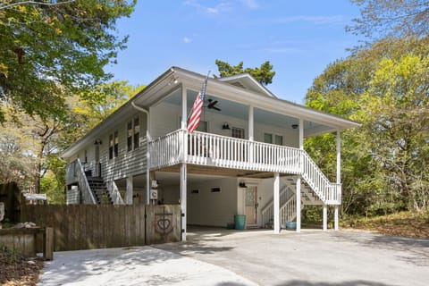 Charming coastal cottage with welcoming covered porch and convenient ground-level parking in a peaceful, tree-lined neighborhood.
