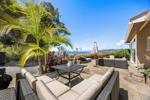Private outdoor patio with comfortable seating, tropical landscaping, and stunning ocean views.