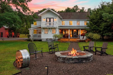 Evening view of the outdoor fire pit with the glowing home in the background.