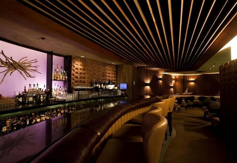 Sip craft cocktails at a sleek bar with warm lighting.