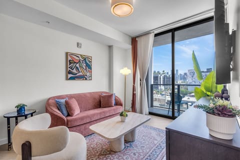 Elegant living room with plush pink velvet seating, curated art gallery wall, Smart TV and designer coffee table — sophisticated and inviting