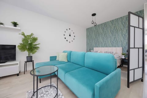 Modern studio apartment with turquoise sofa and elegant botanical wallpaper