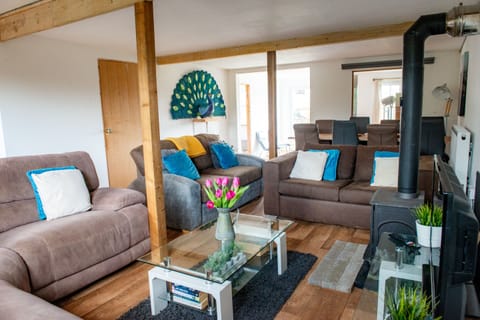 A spacious living area comfortably seating eight guests, featuring a smart TV, DVD player, and wood-burning stove for cosy evenings.